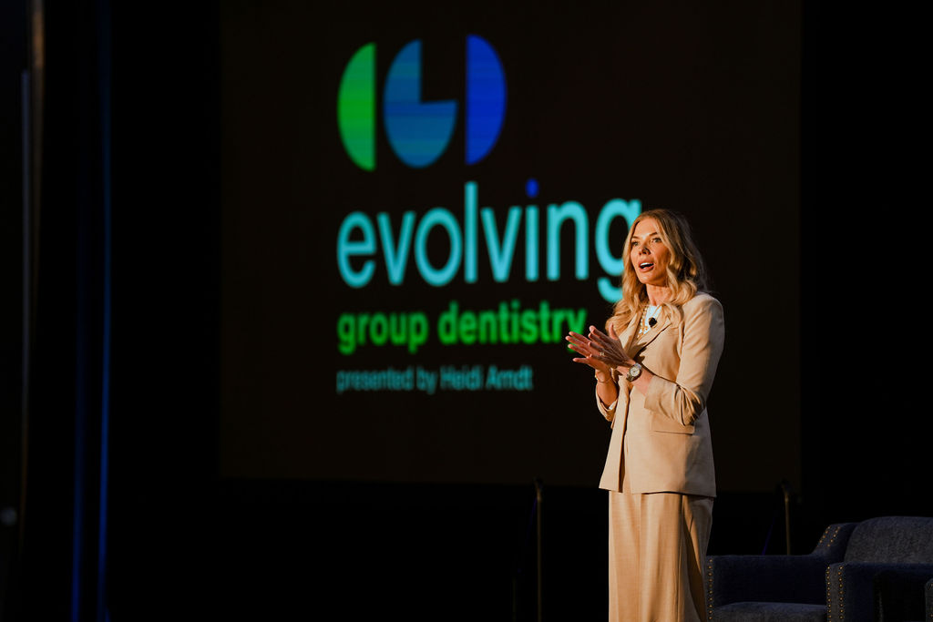 Heidi Arndt presenting onstage in front of an Evolving Group Dentistry backdrop